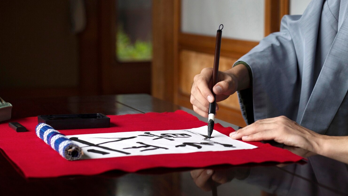 Man practicing japanese handwriting with a brush